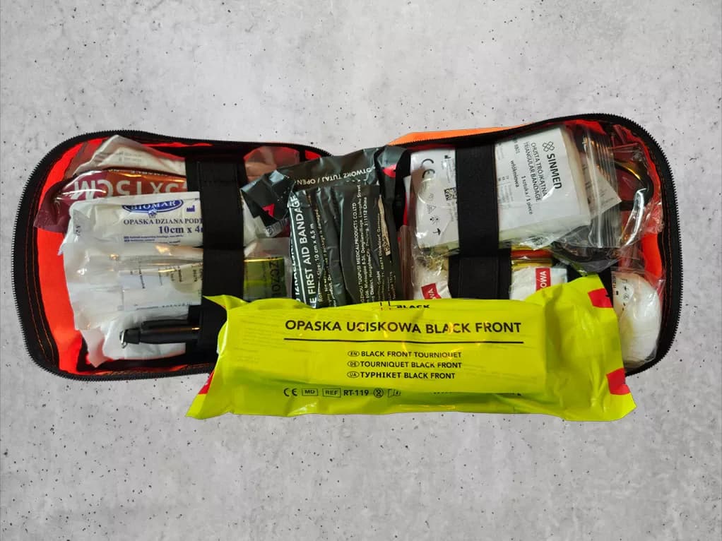 Otwarta apteczka z modułu Pierwsza pomoc: staza taktyczna Black Front, opaska dziana, opatrunek izraelski, chusta trójkątna i opatrunki.